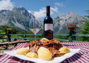 a plate of food with a bottle of wine and a glass at Komovi - Kobil Do Guesthouse in Kolašin