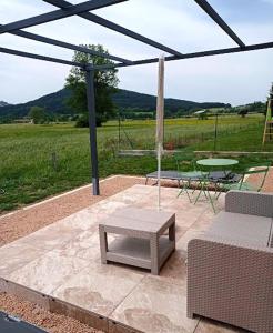 a patio with a table and a bench and an umbrella at Chez Brigitte, un séjour en Haute-Loire in Saint-Germain-Laprade