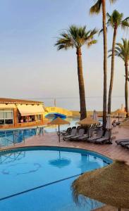 a swimming pool with palm trees and a resort at Donalolaplaya in Mijas Costa