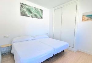 a white bedroom with a bed and a window at Habitación privada con baño y jardín privado in Chiclana de la Frontera