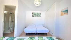 a white room with two beds and a shower at Habitación privada con baño y jardín privado in Chiclana de la Frontera