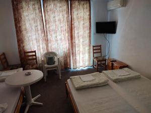 a room with two beds and a table and chairs at Zlatevi Guest House in Obzor