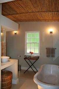 a bathroom with a tub and a sink and a window at The Cottage on 55 in Franschhoek