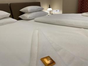 duas camas com lençóis brancos e um objecto dourado em Dózsa Apartman Szeged em Szeged