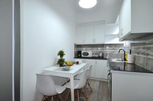 a white kitchen with a white table and chairs at A spacious minimal apatment at Chalandri in Athens