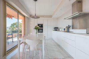 a white kitchen with a white table and chairs at Villefranche Bay View in Villefranche-sur-Mer