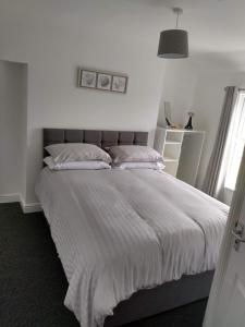 a bedroom with a large bed with white sheets and pillows at place by the sea in Bridlington