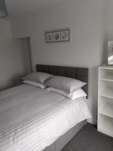 a bedroom with a bed with two pillows and a shelf at place by the sea in Bridlington