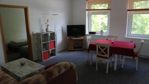 a living room with a red table and a television at Ferienwohnung Rosenstadt in Forst