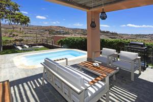 a patio with a swimming pool and chairs and a table at Salobre Los Lagos 26 in Maspalomas