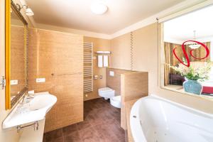 ein Badezimmer mit einer Badewanne, einem Waschbecken und einem WC in der Unterkunft Spa Hotel Vita in Budweis