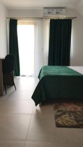 Un dormitorio con una cama verde y una ventana en La Foresteria en Galşa