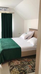 een slaapkamer met een groot bed en een groene deken bij La Foresteria in Galşa