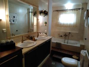 a bathroom with two sinks and a tub and a toilet at La maison de Catherine in Volos