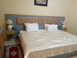 1 dormitorio con 1 cama grande con sábanas y almohadas blancas en Almounia Hotel & Spa, en Taroudant