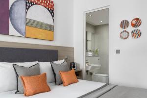 um quarto com uma cama com almofadas laranja e um espelho em Templeton Place by Supercity Aparthotels em Londres