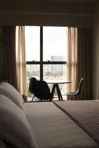 ナタールにある9006 Suites Natal Vista Marのベッド、テーブル、椅子が備わるホテルルームです。