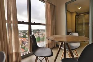 ナタールにある9006 Suites Natal Vista Marのテーブルと椅子、大きな窓が備わる客室です。