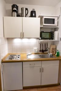 cocina con armarios blancos, fregadero y microondas en Apartment zum Wohlfühlen mitten im Grünen en Lindberg