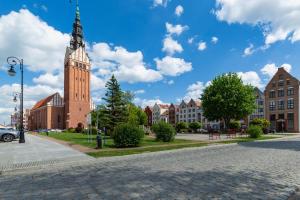 a cobblestone street with a tall building with a clock tower at Apartament Stare Miasto in Elblag