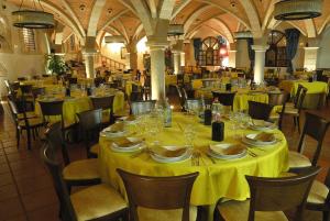 uma sala de jantar com mesas e cadeiras com toalha de mesa amarela em Hotel Termal Abadia de Los Templarios em La Alberca