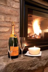 a bottle of champagne and two glasses next to a fireplace at Casale Favilluta in Petrignano