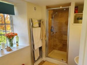 a bathroom with a shower and a vase of flowers at Church Farm House in Cirencester