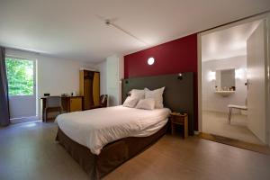 a bedroom with a large bed with a red wall at Kyriad Blois Sud in Vineuil