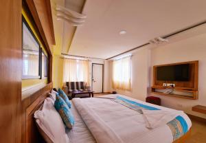 a bedroom with a large bed and a television at Anika Palace by Pepe Inn Hotel in Ooty