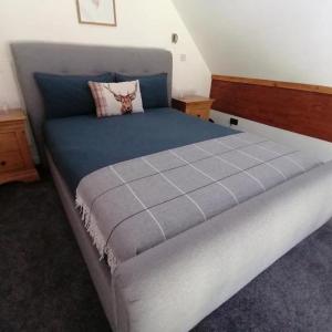 a bedroom with a large bed with a blue blanket at Rest At Last - Highland Apartment with Private hot tub in Whitebridge