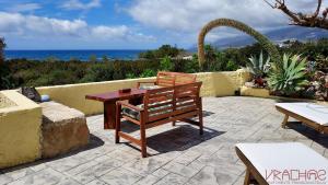 una mesa de madera y un banco en un patio con vistas al océano en Vrachos Apartments, en Frangokastello