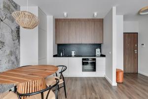 グダニスクにあるGdańsk Comfort Apartaments Łąkowaのキッチン、ダイニングルーム(木製テーブル付)