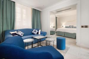 a living room with a blue couch and a bed at Riva Marina Hvar Hotel in Hvar