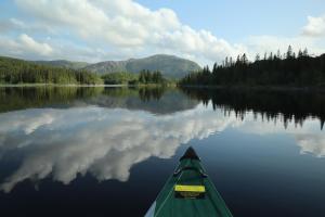 a kayak on a lake with a reflection in the water at Velfjord Camping & Hytter in Velfjord