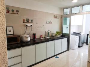 a kitchen with a counter with a sink and a refrigerator at 3BR Mount Austin @Midori Green (1 to 8pax) in Johor Bahru
