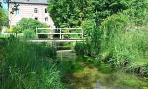 a bridge over a stream in front of a building at Gite de l'Ancien Moulin in Valmont