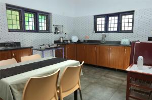 a kitchen with a bed and chairs in a room at Monsoon Apartments in Kannur