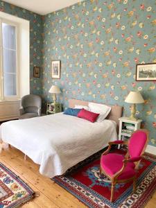 um quarto com uma cama grande e uma cadeira rosa em Demeure de 7 chambres avec piscine privee jardin clos et wifi a Chaniers em Chaniers