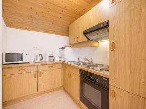 kuchnia z drewnianymi szafkami, kuchenką i kuchenką mikrofalową w obiekcie Apartment Kraxner w Solden +28 zdjęć
