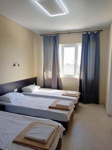 a bedroom with two beds and a window with blue curtains at Sun Village in Gudauta