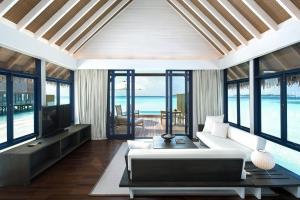 un soggiorno con divano bianco e finestre in vetro di COMO Cocoa Island a Città di Malé