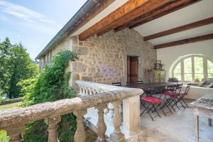 ein Steingebäude mit einem Tisch und Stühlen auf dem Balkon in der Unterkunft Les Pieds dans la Beaume in Joyeuse