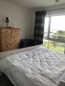 a bedroom with a bed and a dresser and a window at Beautiful Holiday Home in Schull in Schull