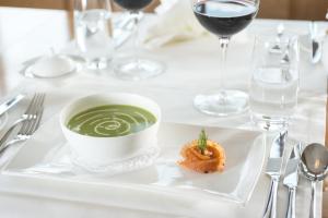 een bord met een kopje groene soep en een garnaal bij Anker Hotel Restaurant in Teufen