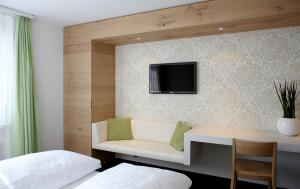 a bedroom with a desk and a tv on a wall at Anker Hotel Restaurant in Teufen