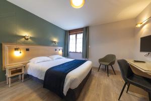 エスカルにあるHôtel L'Escale - Piscine & SPAのベッドとデスクが備わるホテルルームです。