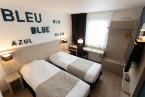 um quarto de hotel com duas camas e uma secretária em Hôtel Relais d'Étretat em Bolbec