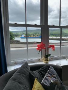 a couch in front of a window with a vase with flowers at Seaview Aurora House - Central Luxury Apartment in Warrenpoint