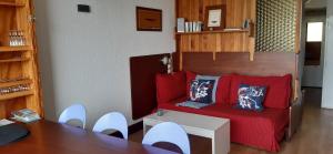 sala de estar con sofá rojo, mesa y sillas en Studio aux pieds des pistes Roche Béranger, en Chamrousse