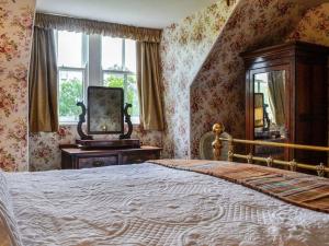 een slaapkamer met een bed, een spiegel en een raam bij Beautiful Traditional secluded country cottage in Sanquhar